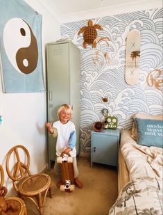 a little boy sitting on top of a wooden chair in a bedroom