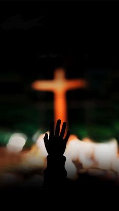 a person's hand in front of a cross