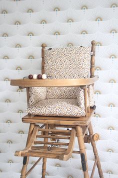 a wooden rocking chair sitting on top of a table next to a wallpapered wall