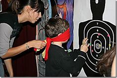 a woman helping a young boy put on a red bandanna in front of an archery target