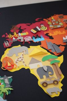 the map of africa is made up of cut out paper animals, trees and buildings