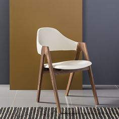 a white chair sitting on top of a rug in front of a brown and tan wall