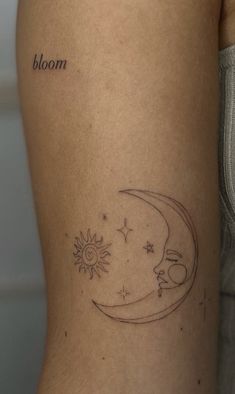 a small tattoo on the back of a woman's leg that reads bloom and has a crescent moon with stars in it