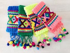 several crocheted hats and pom poms laid out on a table