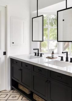 two black and white sinks in a bathroom with large mirrors on the wall above them