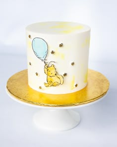 a winnie the pooh birthday cake on a gold and white plate with honeycombs