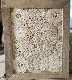 an old wooden frame with crocheted doily on it, sitting on a table