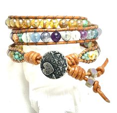 This cute triple wrap bracelet is made for a 6 3/4 wrist (21 1/2 ' of beads )  and is made of Rainbow  🌈 Fluorite, Old World Silver Czech glass, Picasso Czech glass and is double loomed between 2mm chestnut leather cord. The beads are all 6mm except for the Picasso seed beads.  Rainbow Fluorite has a beautiful energy present in its hues of green, purple, blue, and clear which supports multiple chakras, making this the perfect stone for everyone. ... Like Clear Quartz, it amplifies the vibrations of other stones, and like Green Aventurine, Fluorite supports the heart chakra.           ✨🧡Wrap Care 🧡✨ ✨To extend the life of your wrap , please  No chemicals: avoid contact with water, perfumes, sprays and other chemicals.✨No water: remove your jewelry before hand wash, showering, bathing or Gemstone Wrap Bracelet, Triple Wrap Bracelet, Chestnut Leather, Beaded Wrap Bracelets, Rainbow Fluorite, Beaded Wraps, Unique Bracelets, Green Aventurine, Heart Chakra