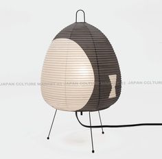 a lamp that is sitting on top of a metal stand with a black and white shade