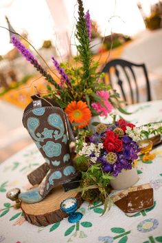 cowboy boots and flowers on a table at an outdoor wedding reception in the country style