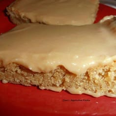 two pieces of cake sitting on top of a red plate covered in frosted icing