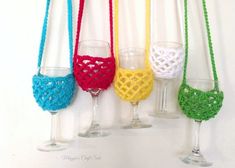 four wine glasses hanging on a wall with crocheted handles and ties around them