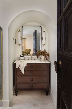 an arched doorway leads to a bathroom with a sink and mirror on the countertop