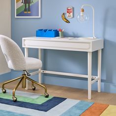 a white desk with a chair next to it and a blue wall in the background