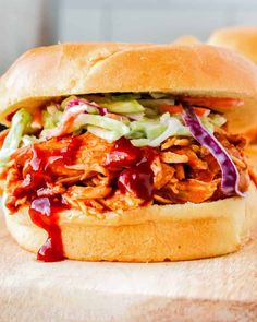 a pulled pork sandwich with coleslaw and slaw on a wooden cutting board