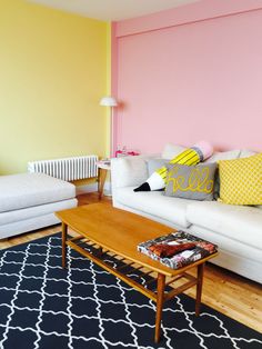 a living room with two couches and a coffee table in front of a pink wall