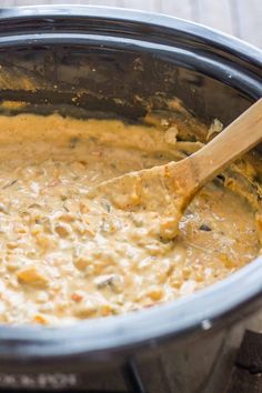 a wooden spoon in a crock pot filled with food and sauce on a table