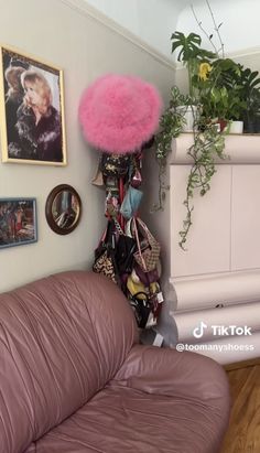 a living room with pink furniture and pictures on the wall, plants in vases