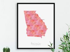 a watercolor map of the state of virginia on a white wall next to a potted plant