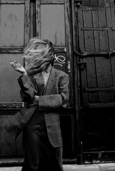 a woman is walking down the street with her hair blowing in front of her face