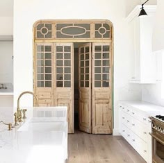 a kitchen with white cabinets and wooden doors