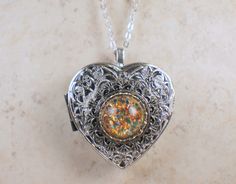 "Music box pendant. This heart shaped music box pendant is inspired by the gorgeous music box pendants of era's gone by. Music box is pill box size, please look at the dimensions for exact size. A perfect silvertone heart locket has been adorned with a layer of filigree and a Monet Red Sunset glass fire opal cabochon. The cabochon is set in a silver bezel. The filigree and silver bezel have been finished with resin to preserve the beauty of this pendant. The music box winds from a key on the bac Amber Locket Jewelry For Gift, Amber Locket Jewelry As A Gift, Amber Heart Pendant Jewelry Gift, Heart Pendant Amber Jewelry For Gift, Victorian Amber Jewelry For Gift, Victorian Amber Jewelry For Gifts, Heart Pendant Locket Necklace With Filigree For Gift, Ornate Necklace For Valentine's Day Gift, Music Locket