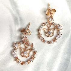 Detail & Description Transform into a vision of elegance with our Fluttering Rose Gold Wreath Drop Earrings. Delicate butterflies dance amidst a wreath of flowers, all crafted from exquisite rose gold. Elevate your style with this dreamy jewelry, perfect for any occasion. The earring posts are in silver which are good for sensitive ears. It is also a perfect gift idea for special events, occassions and celebrations like birthday/anniversary/Valentine's Day/Christmas. Optional gift wrapping servi Feminine Dangle Rose Gold Jewelry, Feminine Rose Gold Dangle Jewelry, Rose Gold Cubic Zirconia Flower Earrings For Party, Delicate Rose Gold Flower Earrings For Anniversary, Rose Gold Flower Earrings For Wedding, Rose Gold Dangle Flower Earrings For Anniversary, Rose Gold Cubic Zirconia Flower Earrings, Feminine Rose Gold Earrings For Anniversary, Dainty Rose Gold Flower Drop Earrings