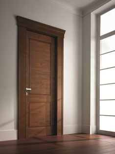 an empty room with a wooden door in the center and hard wood flooring on the other side