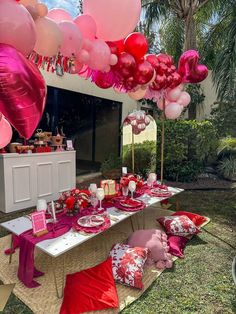 a table set up with pink and red balloons