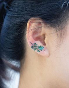 a woman's ear with green leaves on it