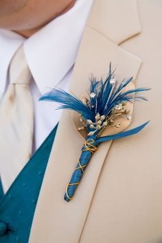 a boutonniere with blue feathers on it is worn by a man in a suit