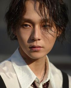 a young man with black hair wearing a white shirt and maroon tie, looking at the camera