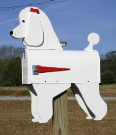 a white dog mailbox sitting on top of a wooden post