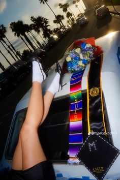 a woman's legs are propped up on the hood of a police car with ribbons and flowers