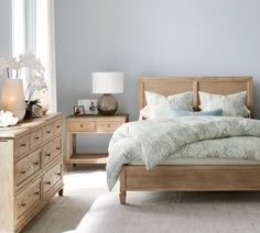 a bed sitting in a bedroom next to a dresser and lamp on top of a table