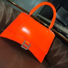 Authentic Balenciaga Bag Day Glow Orange Brand Spanking New Never Used **Missing Long Orange Strap*** Hourglass Small Handbag In Orange Shiny Box Calfskin, Aged Silver Hardware Dimensions : L9 X H5,9 X W3,9 Inch Shiny Box Calfskin Handbag Curvilinear Base One Handle Studded Magnet Closure Tone-On-Tone B Logo Hardware 1 Back Pocket 1 Inner Zipped Pocket Nappa Lambskin Lining Made In Italy Wipe With A Soft Cloth Material: 100% Calfskin Designer Orange Shoulder Bag For Shopping, Orange Double Handle Evening Bag, Designer Orange Top Handle Shoulder Bag, Orange Top Handle Shoulder Bag With Dust Bag, Designer Orange Satchel, Chic Orange Satchel For Evening, Chic Orange Evening Satchel, Designer Orange Satchel Shoulder Bag, Designer Orange Shoulder Bag