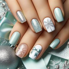 a woman's hand with green and white nail polishes on her nails, decorated with snowflakes