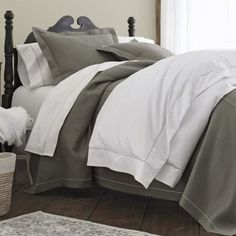 a bed with white and grey sheets in a bedroom