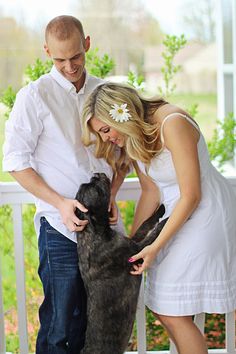 a man and woman petting a dog on the porch