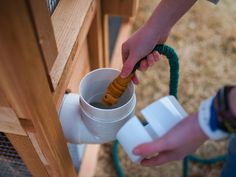 a person is holding a hose and pouring water into a cup that has a tube attached to it