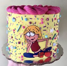 a hand holding a cake decorated with an image of a cartoon character on the frosting and sprinkles