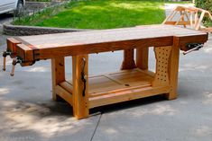 a wooden workbench sitting on top of a sidewalk next to a green lawn