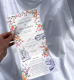 a person holding up a paper with an orange and white floral design on the front