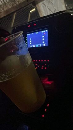 a glass filled with liquid sitting on top of a table next to a computer screen