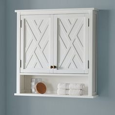 a white cabinet with two doors and some towels on the shelf next to it in a bathroom