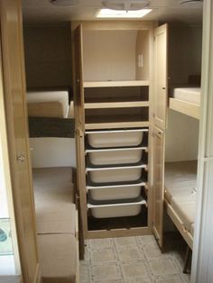 the inside of a small room with bunk beds and storage containers on each side of the door