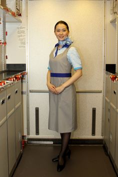 a woman is standing in the kitchen wearing an apron and blue ribbon around her neck