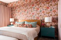 a bedroom with pink floral wallpaper and two nightstands in front of the bed