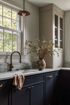 a vase filled with flowers sitting on top of a kitchen counter next to a window