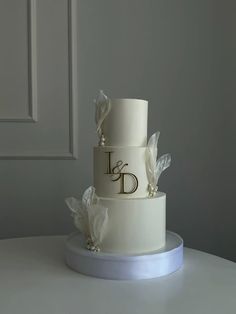 a three tiered wedding cake with flowers on the top and initials on the side